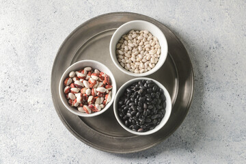 Bowls with raw beans on light background