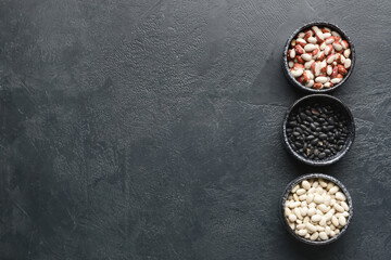 Bowls with raw beans on dark background