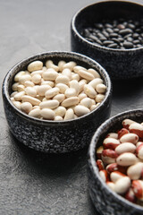 Bowls with raw beans on dark background, closeup