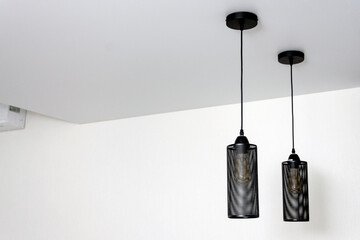 Black metal lamps on the white ceiling in the interior.