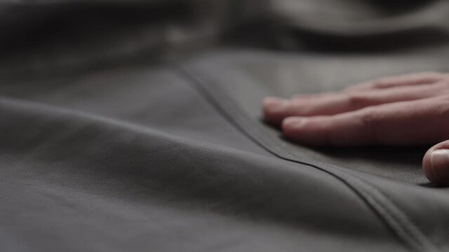Slow motion shot man touching fine leather closeup