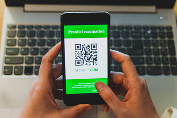 Woman holding smartphone with coronavirus vaccine passport app. Status is valid.