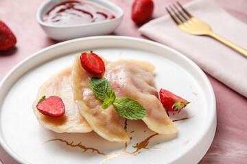 Plate with tasty strawberry dumplings and sauce on color background, closeup