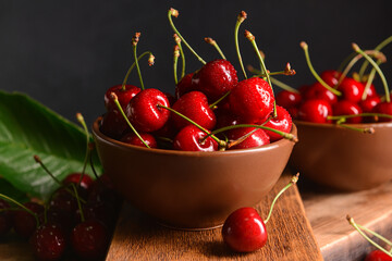 Bowl with sweet cherries on dark background