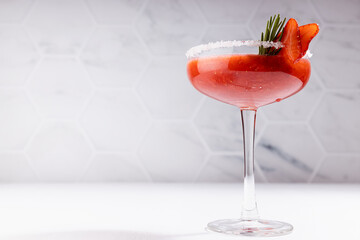 Tropical fresh strawberry juice with pulp in high glass goblet decorated green rosemary twig, sugar...
