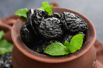 Bowl with tasty prunes on table, closeup