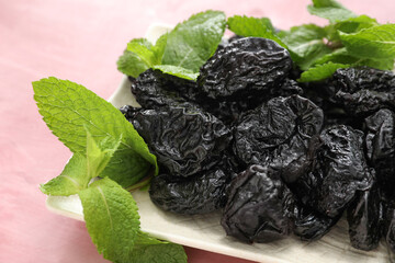 Plate with tasty prunes on color background, closeup