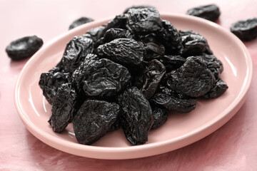 Plate with tasty prunes on color background, closeup