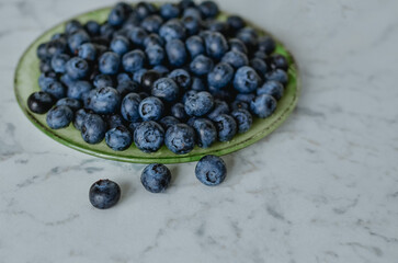 Blueberries on a plate. Light-colored table top.
