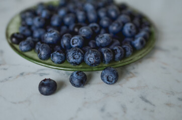 Blueberries on a plate. Light-colored table top.
