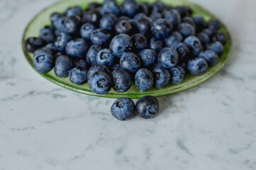 Blueberries on a plate. Light-colored table top.
