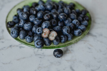 Blueberries on a plate. Light-colored table top.
