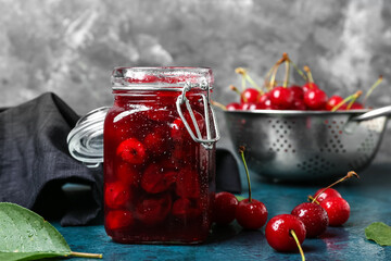 Jar with tasty cherry jam on table