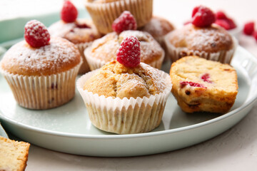 Tray with tasty raspberry muffins on light background, closeup