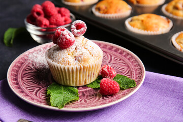 Plate with tasty raspberry muffin on dark background, closeup