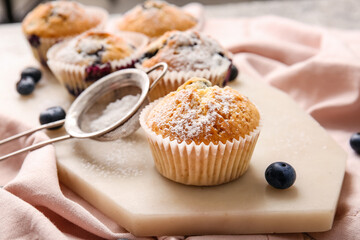 Board with tasty blueberry muffins on table
