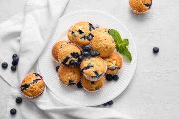 Plate with tasty blueberry muffins on light background - Powered by Adobe