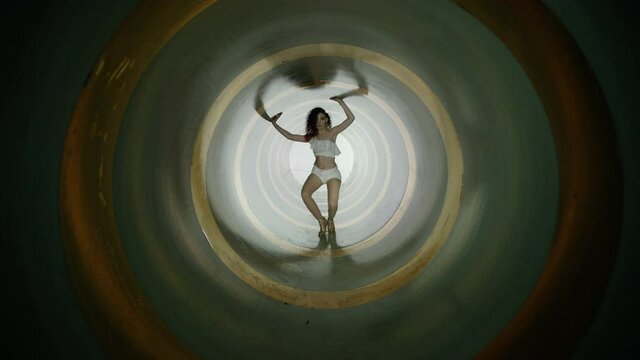 A beautiful brunette sexy girl , woman dancing inside circle tube . Against colored & gray background . Real decoration . None computer graphics . Shot on Arri Alexa Cinema Camera in 4K .