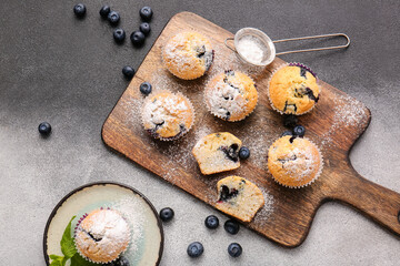 Composition with tasty blueberry muffins and berries on black and white background