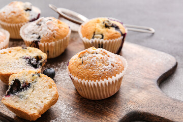 Board with tasty blueberry muffins on dark background, closeup