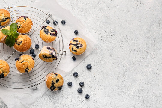 Grid with tasty blueberry muffins on light background, closeup
