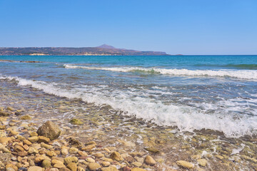 Waves with foam on Aegean sea coast in Crete Greece.