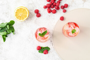 Glasses with tasty raspberry lemonade on light background