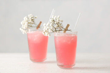 Glasses with tasty cocktail and beautiful gypsophila flowers on light background