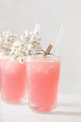 Glasses with tasty cocktail and beautiful gypsophila flowers on light background