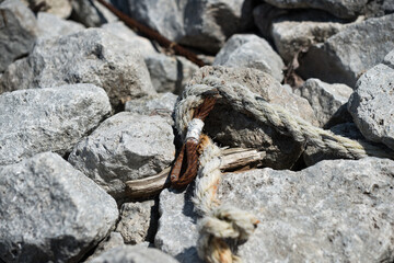rusty metal guy wire and old rope on the rocks