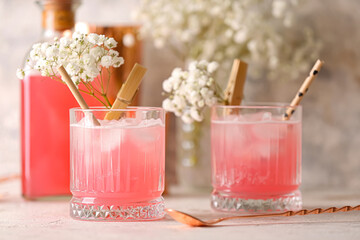 Glasses with tasty cocktail and beautiful gypsophila flowers on light background