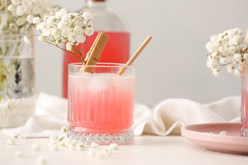 Glasses with tasty cocktail and beautiful gypsophila flowers on table