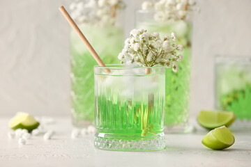 Glasses with tasty cocktail and beautiful gypsophila flowers on light background