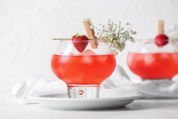 Glasses with tasty cocktail and beautiful gypsophila flowers on light background