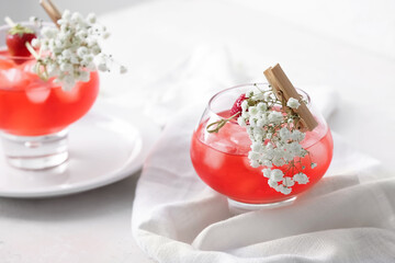 Glasses with tasty cocktail and beautiful gypsophila flowers on light background