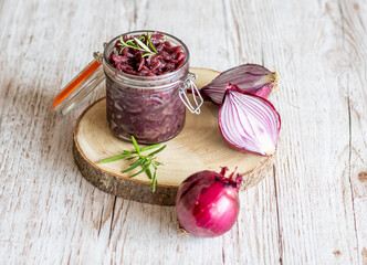 Red onion marmalade placed on wooden trunk with wood texture background. Jam from onion is...
