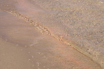Clear waves and colorful sand on tropical sandy beach in Crete Greece.