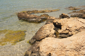 Surface of clear water on tropical sandy beach with stones in Crete Greece.