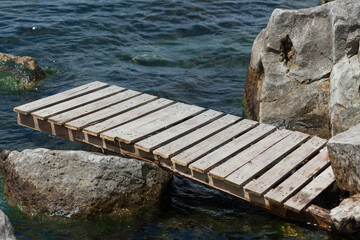 Fototapeta premium unmoored pier washed up against the rocks