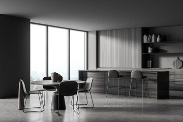 Dark grey kitchen space with round dining table. Corner view