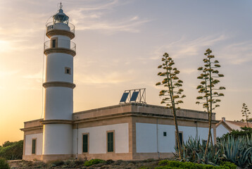 Lighthouse of the Mallorcan town of Ses Salines at sunset in summer. Golden hour