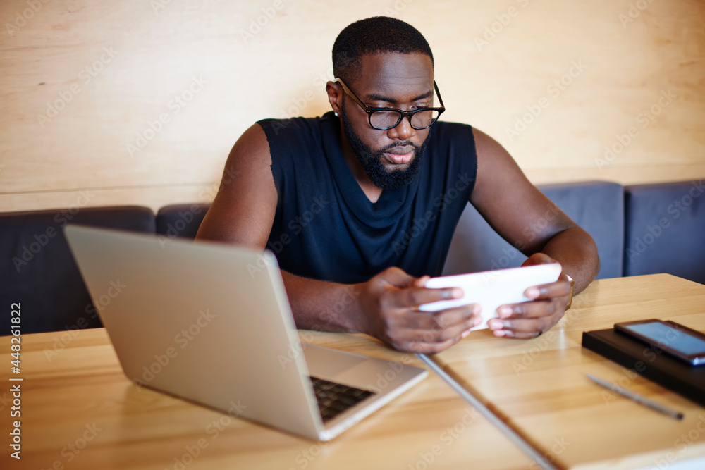 Poster millennial male blogger with laptop using touch pad technology for browsing web publication while ne