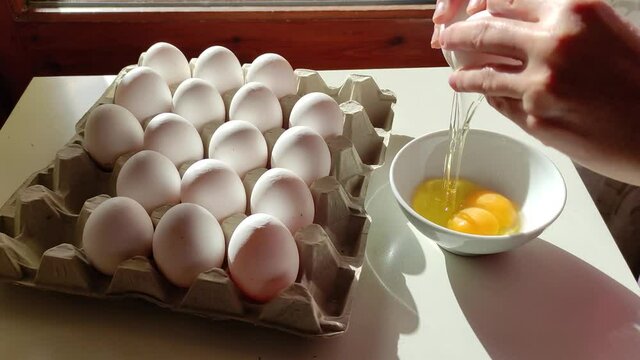 Lady hand breaking fresh two yolk egg into bowl