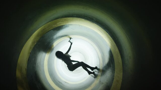 A silhouette of beautiful sexy girl , woman dancing inside circle tube . Against colored & gray background . Real decoration . None computer graphics . Shot on Arri Alexa Cinema Camera in 4K .