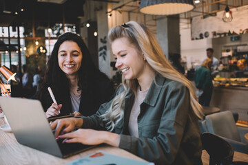 Smiling women reading messages from laptop