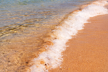 Pure clear water in the sea, sun glare, waves and sea sand. Calm sea water background