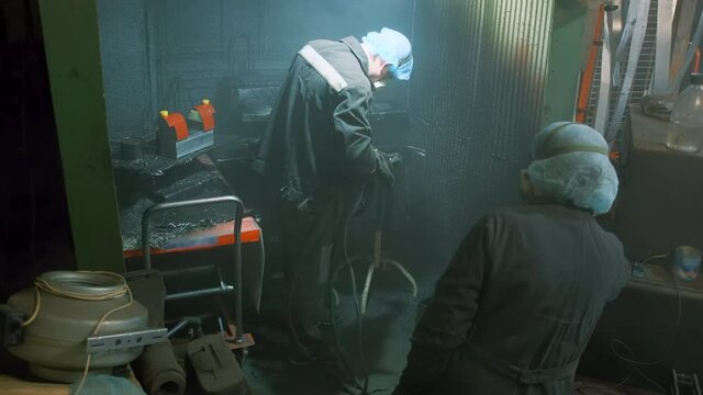 A man in a factory sprays polyurethane on a part. Spraying polyurethane on metal to protect against corrosion and abrasion. Coating with two-component cold curing polyurethanes for industrial products