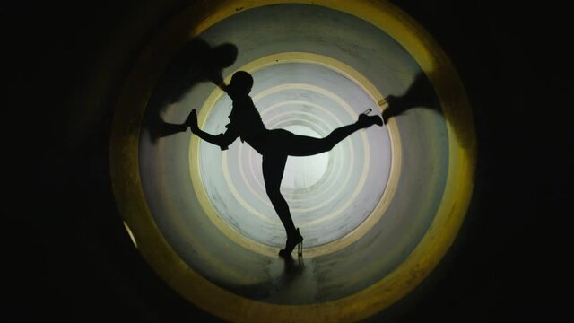 A silhouette of beautiful sexy girl , woman dancing inside round circle tube . Against colored & gray background . Real decoration . None computer graphics . Shot on Arri Alexa Cinema Camera in 4K .
