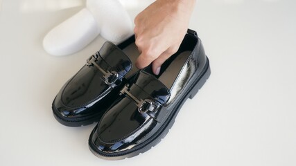 A young girl is preparing for the start of the school year and unpacking new shiny black loafers. 