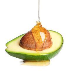 Pouring essential oil onto cut avocado on white background